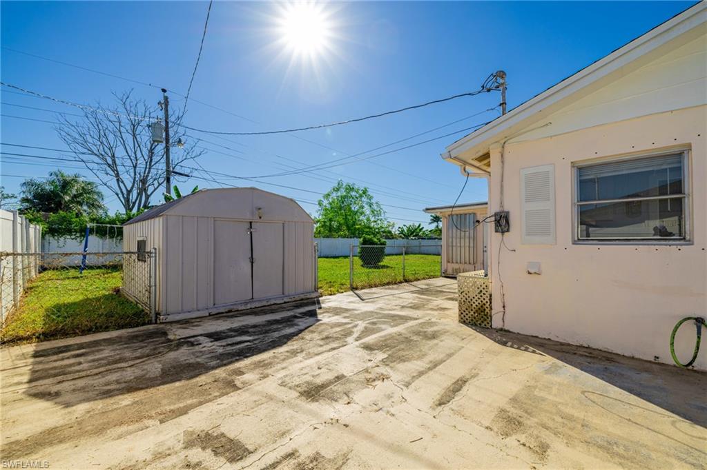 339 Beachwood Road Lehigh Acres, FL 33936 - Photo 24 of 32 Fenced backyard with a storage unit and a patio area