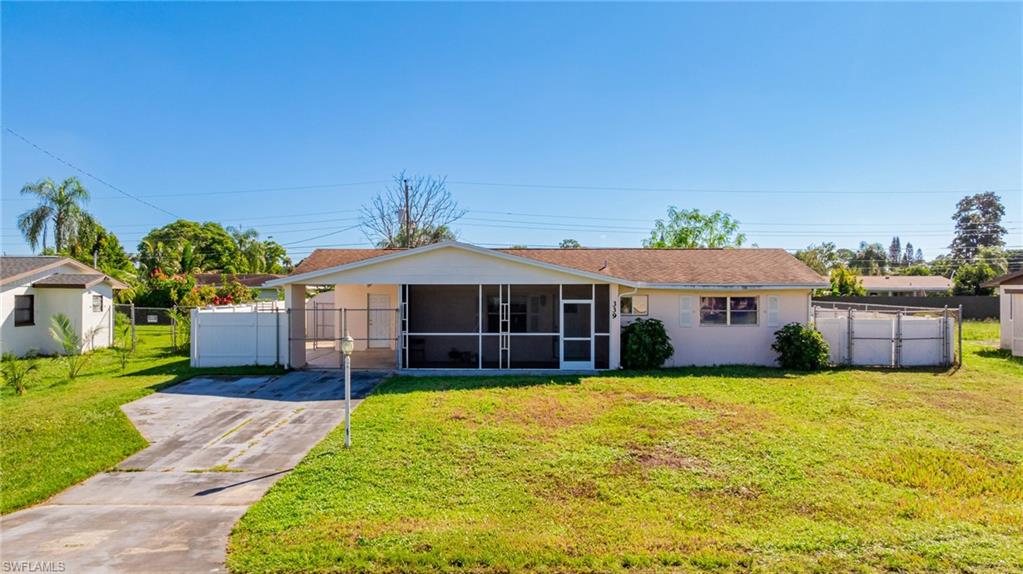 339 Beachwood Road Lehigh Acres, FL 33936 - Photo 29 of 32 Ranch-style home with a sunroom, a gate, concrete driveway, and stucco siding