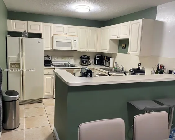 a kitchen with stainless steel appliances a sink a refrigerator a microwave and cabinets