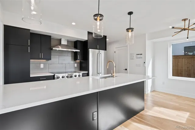 a large kitchen with stainless steel appliances a large counter top a stove and a refrigerator