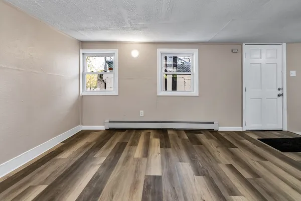 a view of an empty room with wooden floor and a window
