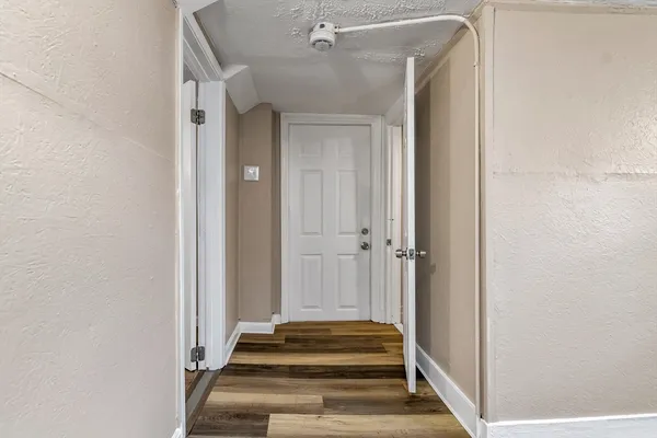 a view of a hallway with a door and wooden floor