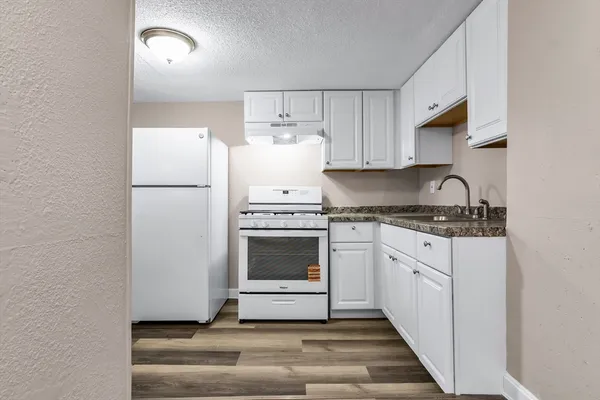 a kitchen with granite countertop white cabinets and white appliances