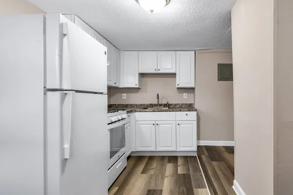 a kitchen with granite countertop white cabinets and white appliances