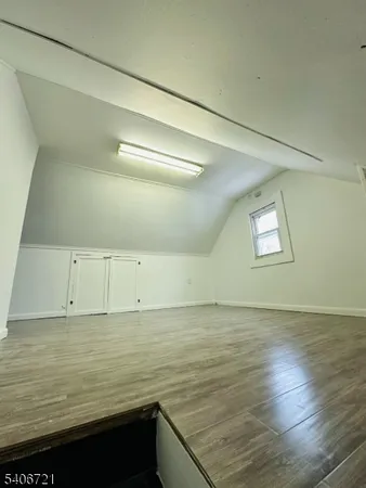 a view of an empty room with wooden floor and stairs