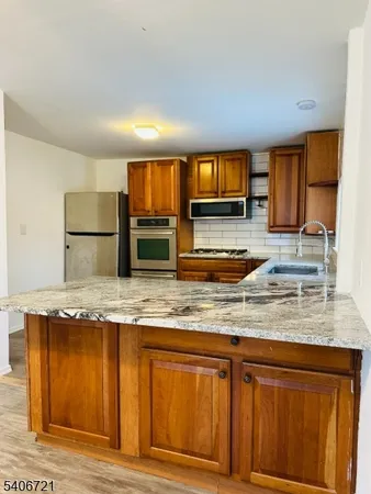 a kitchen with granite countertop a stove a sink and a refrigerator