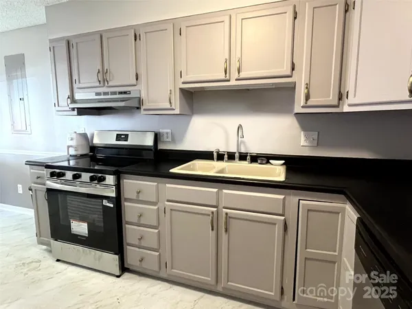 a kitchen with stainless steel appliances granite countertop white cabinets and a stove a sink
