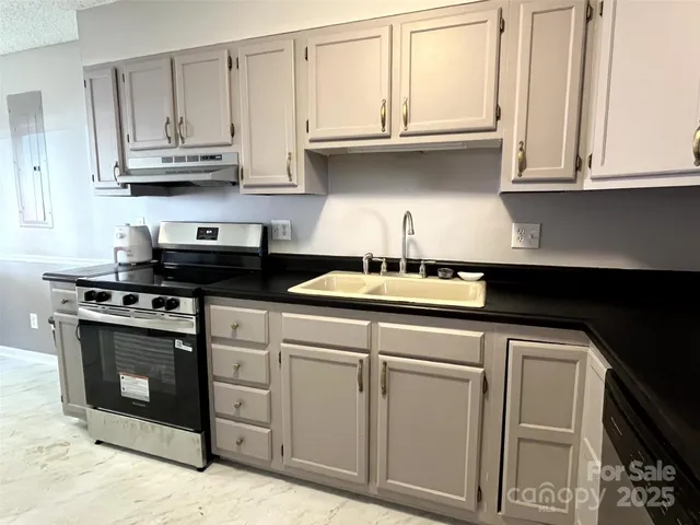 a kitchen with stainless steel appliances granite countertop white cabinets and a stove a sink