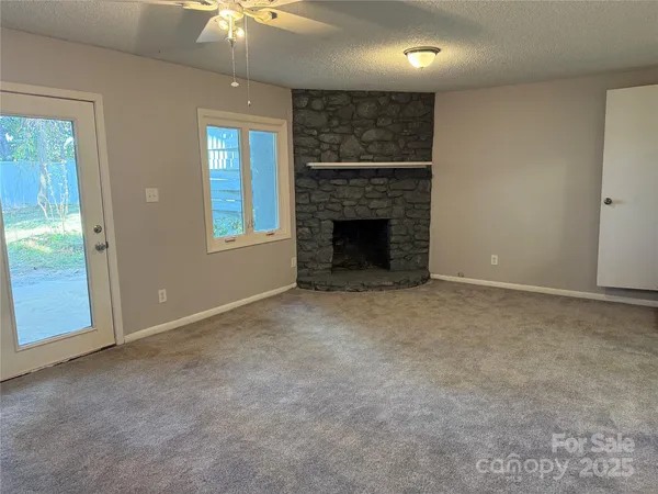 a view of an empty room with a fireplace and a window