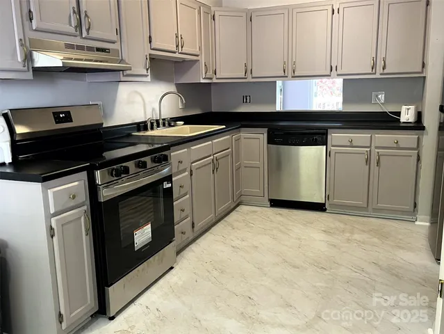 a kitchen with stainless steel appliances granite countertop a stove a sink and cabinets