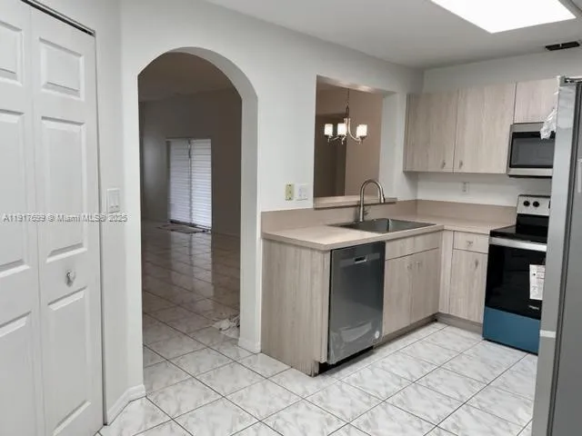 a kitchen with stainless steel appliances a sink cabinets and a window