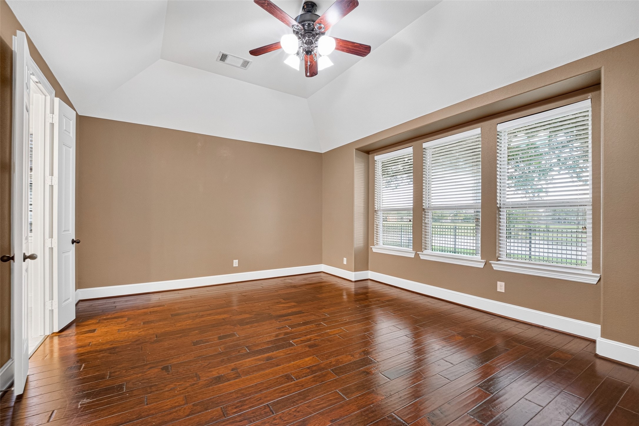7930 Summer Night Lane Rosenberg, TX 77469 - Photo 20 of 48 Spacious primary bedroom featuring hardwood flooring, tray ceiling, and oversized windows with peaceful backyard views.