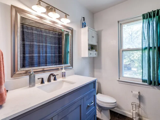 a bathroom with a sink vanity mirror and toilet
