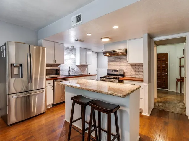a kitchen with granite countertop a refrigerator and a stove top oven