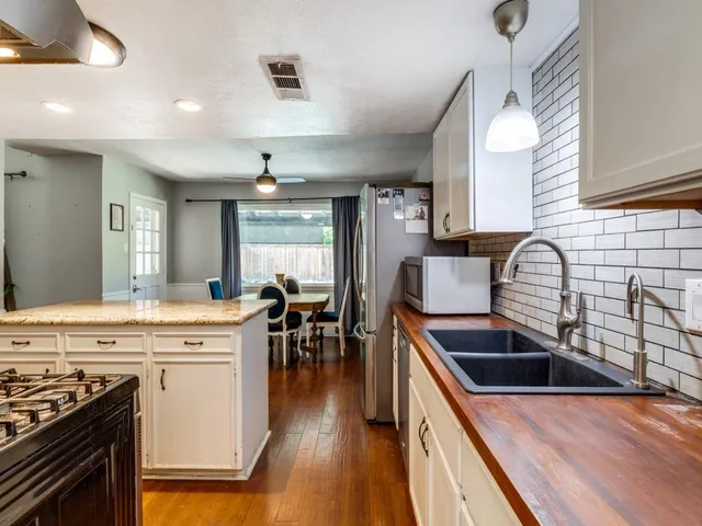 a kitchen that has a sink a stove and wooden floor