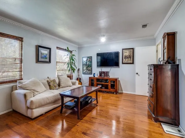 a living room with furniture a flat screen tv and a refrigerator