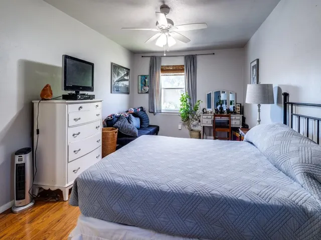a bedroom with a bed and a flat tv screen on dresser