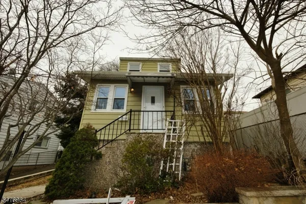 a front view of a house with a tree