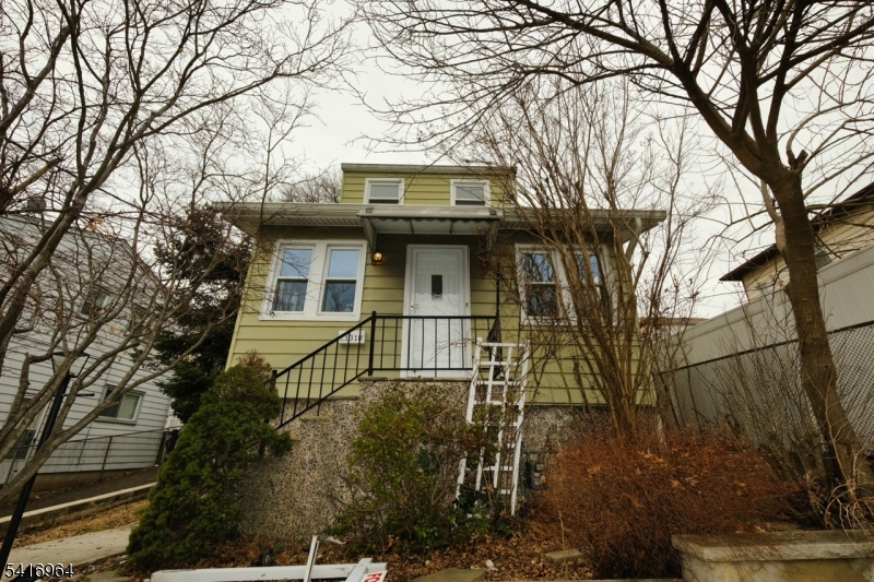 a front view of a house with a tree