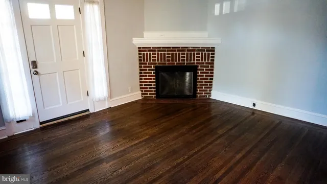 an empty room with wooden floor fireplace and windows