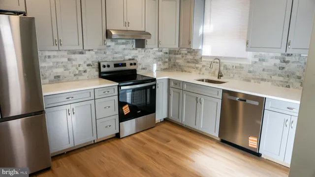 a kitchen with stainless steel appliances granite countertop a stove a sink and white cabinets