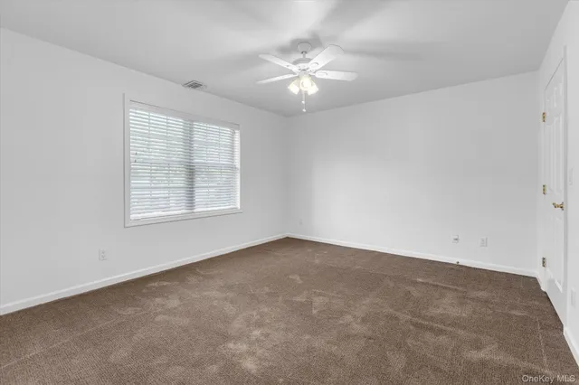an empty room with windows and chandelier fan