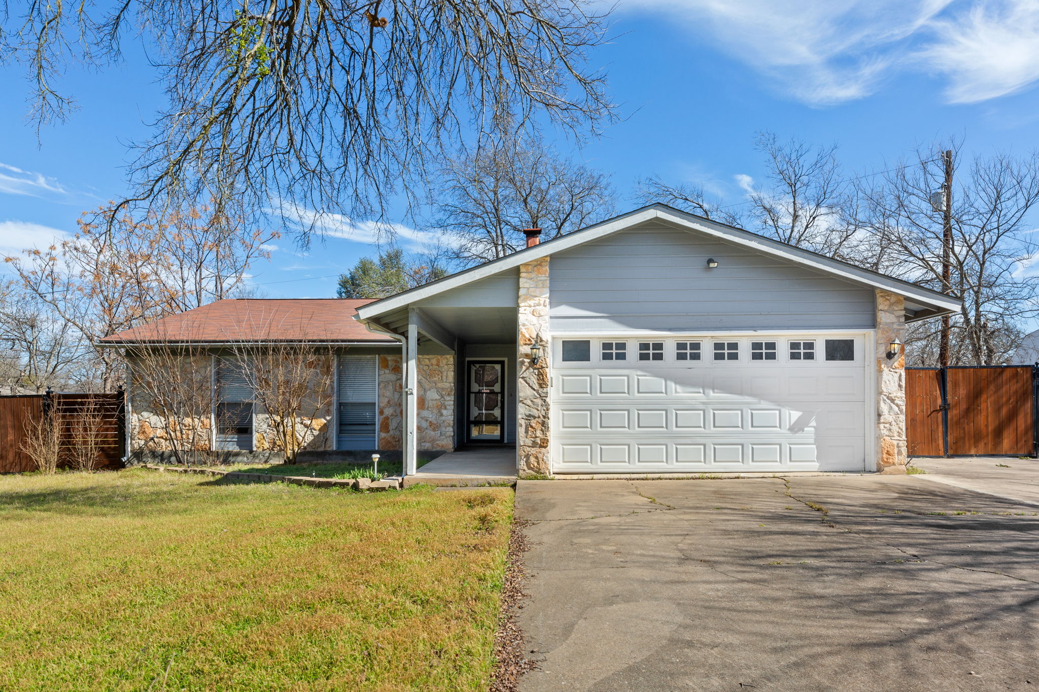 View of front facade with stone siding, concrete driveway, an attached garage, and a chimney