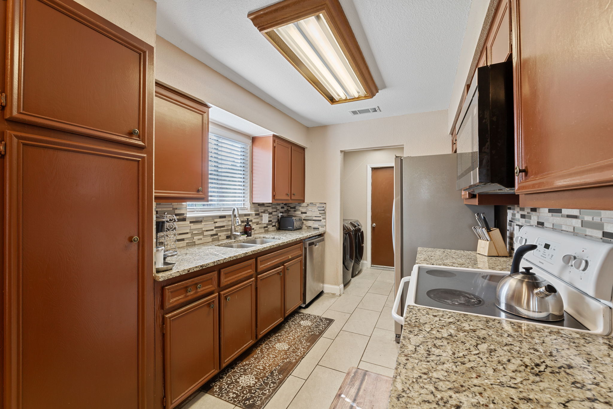 1602 Plateau Ridge Cedar Park, TX 78613 - Photo 5 of 29 Kitchen featuring white electric range, black microwave, tasteful backsplash, independent washer and dryer, and light stone countertops