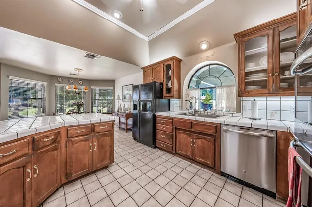 a large kitchen with kitchen island granite countertop a large window a sink and cabinets