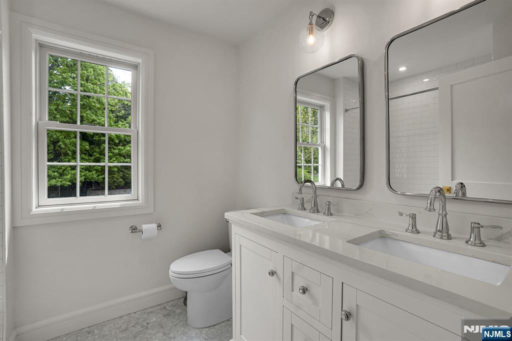 331 Wastena Terrace Ridgewood, NJ 07450 - Photo 34 of 49 a bathroom with a granite countertop toilet a sink a mirror and a window