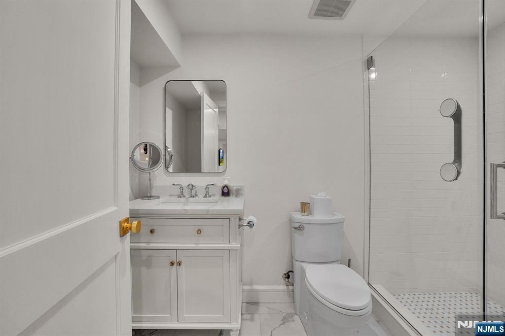 331 Wastena Terrace Ridgewood, NJ 07450 - Photo 42 of 49 a bathroom with a toilet a sink a mirror and vanity