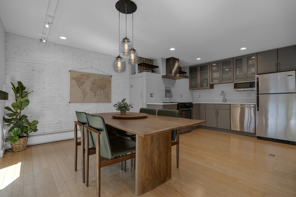 9 Appleton Street, Unit M1 Boston, MA 02116 - Photo 8 of 24 a kitchen with stainless steel appliances kitchen island a table chairs in it and wooden floors