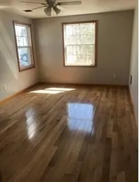 an empty room with wooden floor and windows