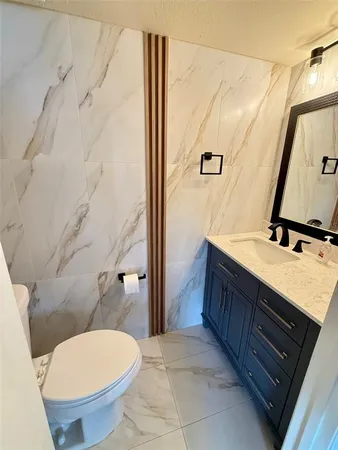 a bathroom with a granite countertop toilet sink and mirror