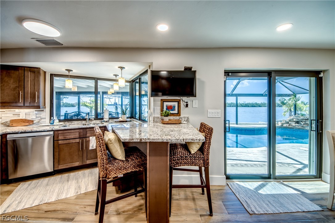 11599 Island Avenue Matlacha, FL 33993 - Photo 11 of 38 a kitchen with stainless steel appliances granite countertop a stove a sink a microwave a dining table and chairs
