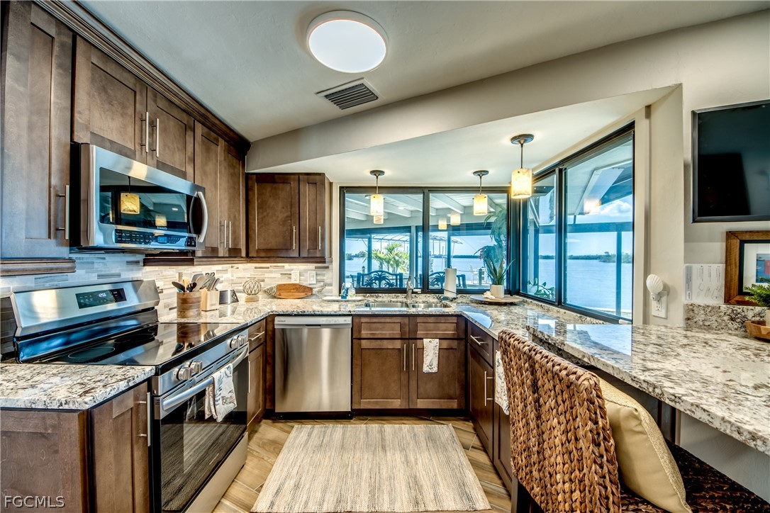 11599 Island Avenue Matlacha, FL 33993 - Photo 15 of 38 a kitchen with stainless steel appliances granite countertop sink stove top oven and granite counter top