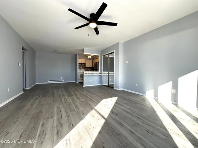 a view of a kitchen with wooden floor a sink a ceiling fan and windows