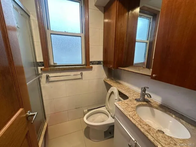 a bathroom with a granite countertop toilet sink and mirror