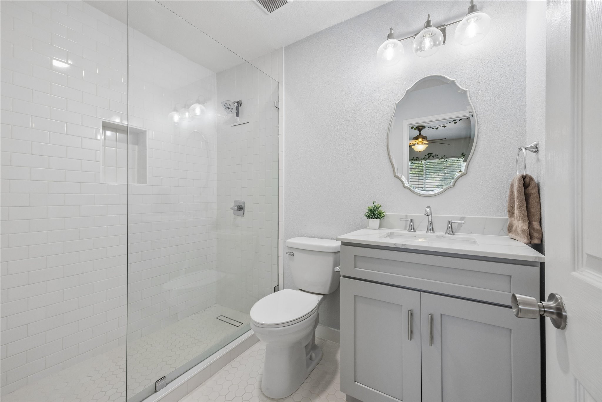 304 East 33rd Street, Unit 4 Austin, TX 78705 - Photo 1 of 15 Contemporary bathroom featuring a frameless glass shower enclosure with white subway tile, a built-in shower niche, and hexagonal floor tiles