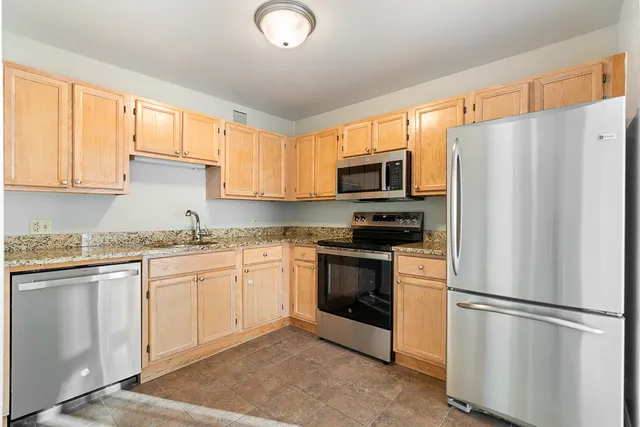 a kitchen with stainless steel appliances granite countertop a refrigerator stove a sink dishwasher and microwave