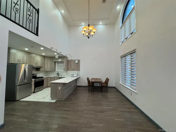 a kitchen with stainless steel appliances kitchen island granite countertop a refrigerator a stove a sink and a dining table with wooden floor