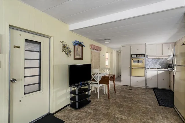 a living room with furniture a flat screen tv and kitchen view