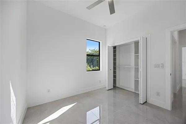 an empty room with ceiling fan and window