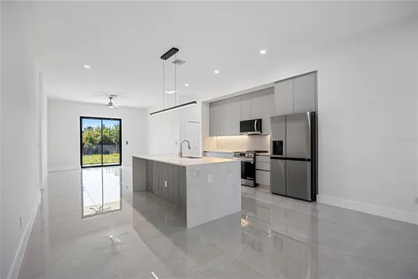 a large white kitchen with a refrigerator a oven a counter space and a window