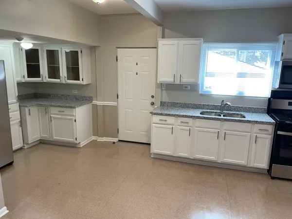 a kitchen with granite countertop a stove sink and cabinets