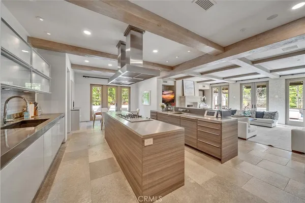 a large white kitchen with kitchen island a large counter space a sink stainless steel appliances and cabinets