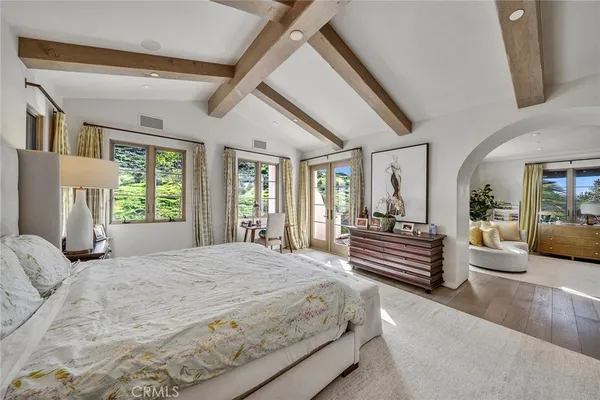 a bedroom with a large bed couch and windows