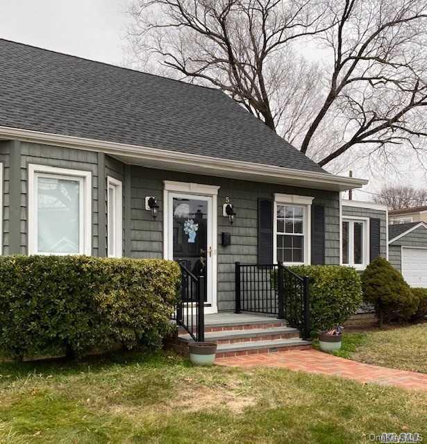 a view of a house with a big yard plants and large tree
