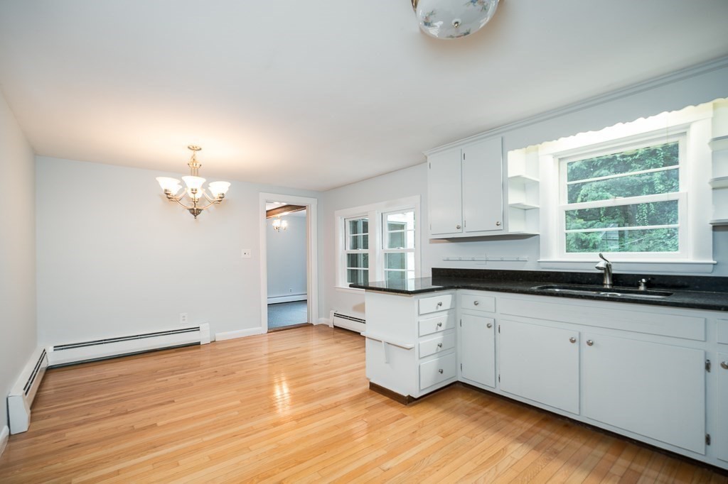4 Cedarview Road Ipswich, MA 01938 - Photo 8 of 20 a kitchen with granite countertop white cabinets a sink a window and a wooden floor