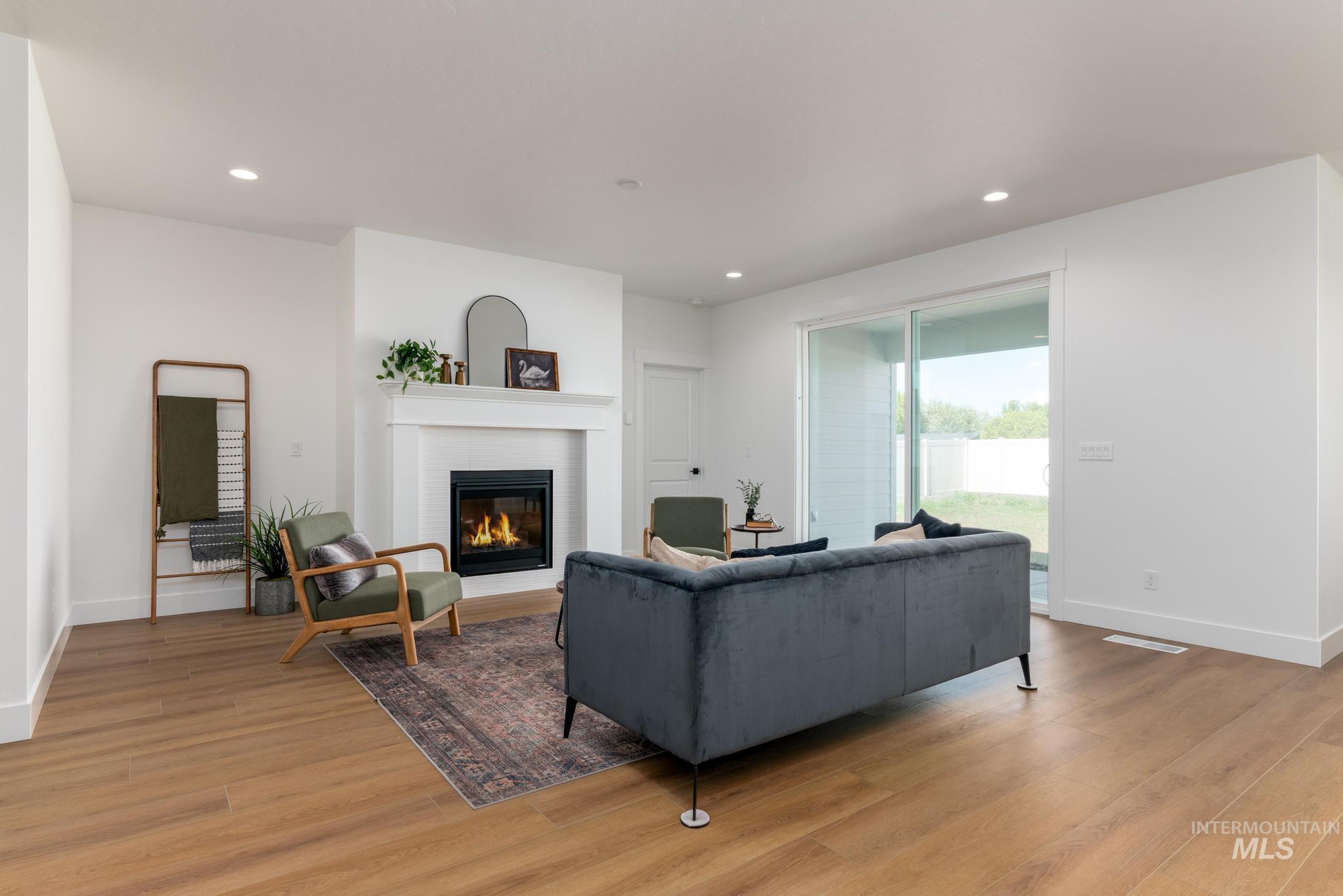 1925 Buckbrush Avenue Middleton, ID 83644 - Photo 3 of 20 Living area featuring a fireplace with a white mantel, recessed lighting, wood-finish flooring, a sliding glass door, and white baseboards